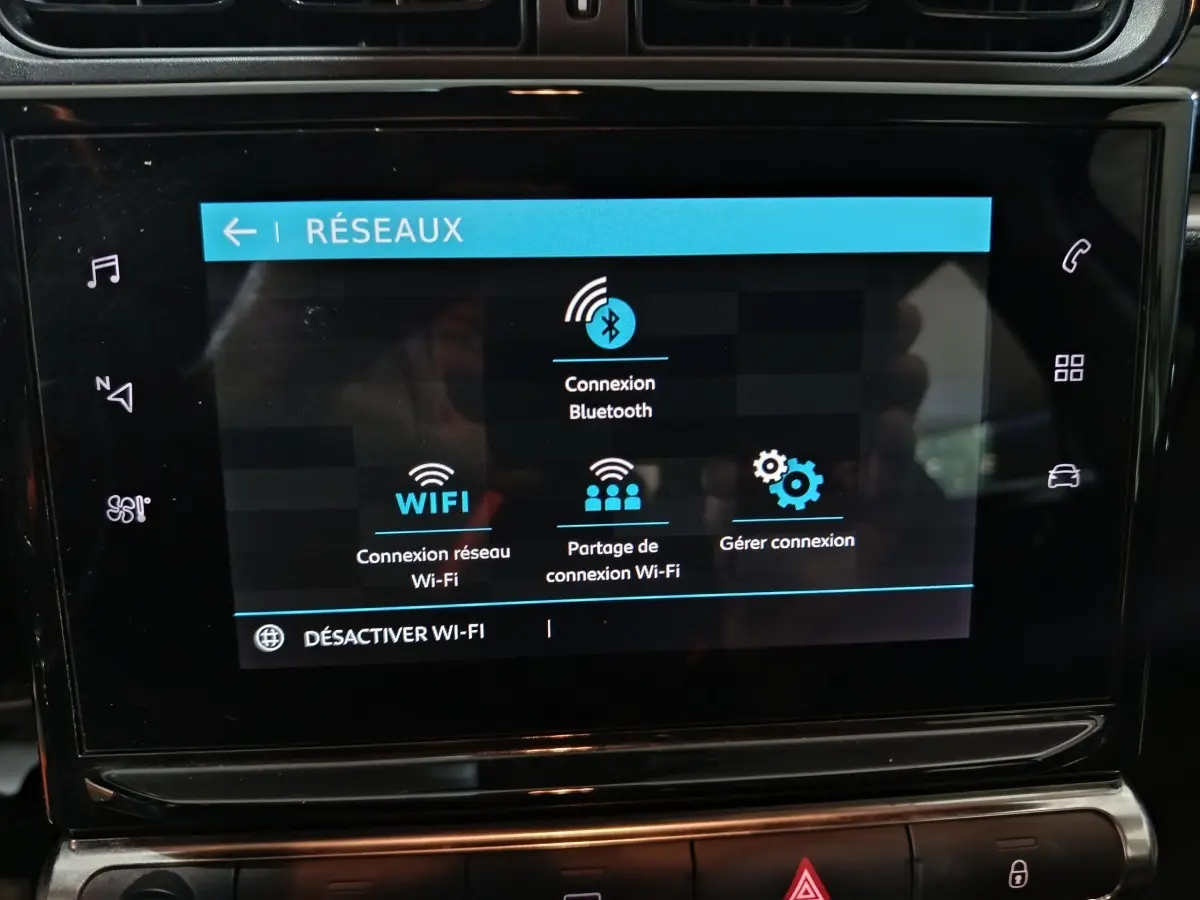 Écran tactile central du tableau de bord de la Citroën C3 2024 gris foncé affichant les options de connexion réseau Bluetooth et Wi-Fi.