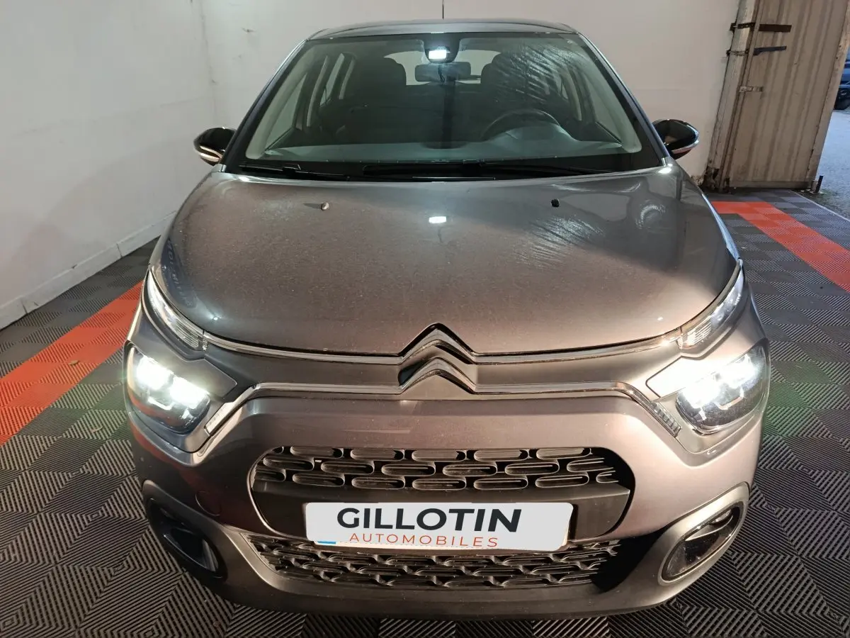 Vue avant d'une Citroën C3 gris foncé avec phares LED allumés dans un garage fermé.