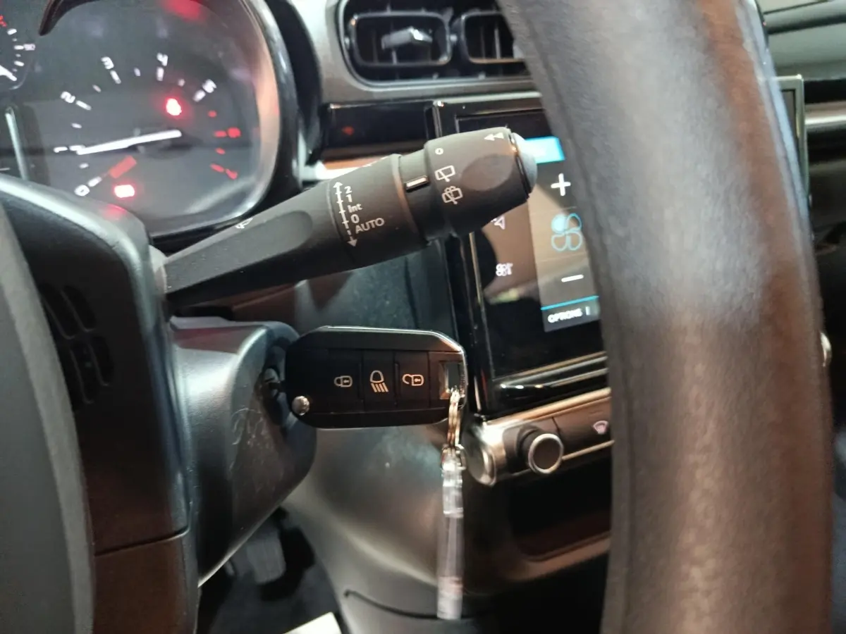 Gros plan intérieur sur le volant et la clé de contact de la Citroën C3 2024, avec écran tactile et commandes au volant visibles.