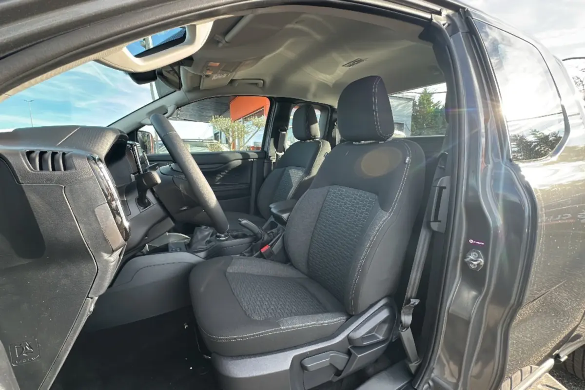 Vue intérieure côté conducteur du Ford Ranger gris iconic 2025, montrant les sièges avant et le volant multifonctions en cuir.