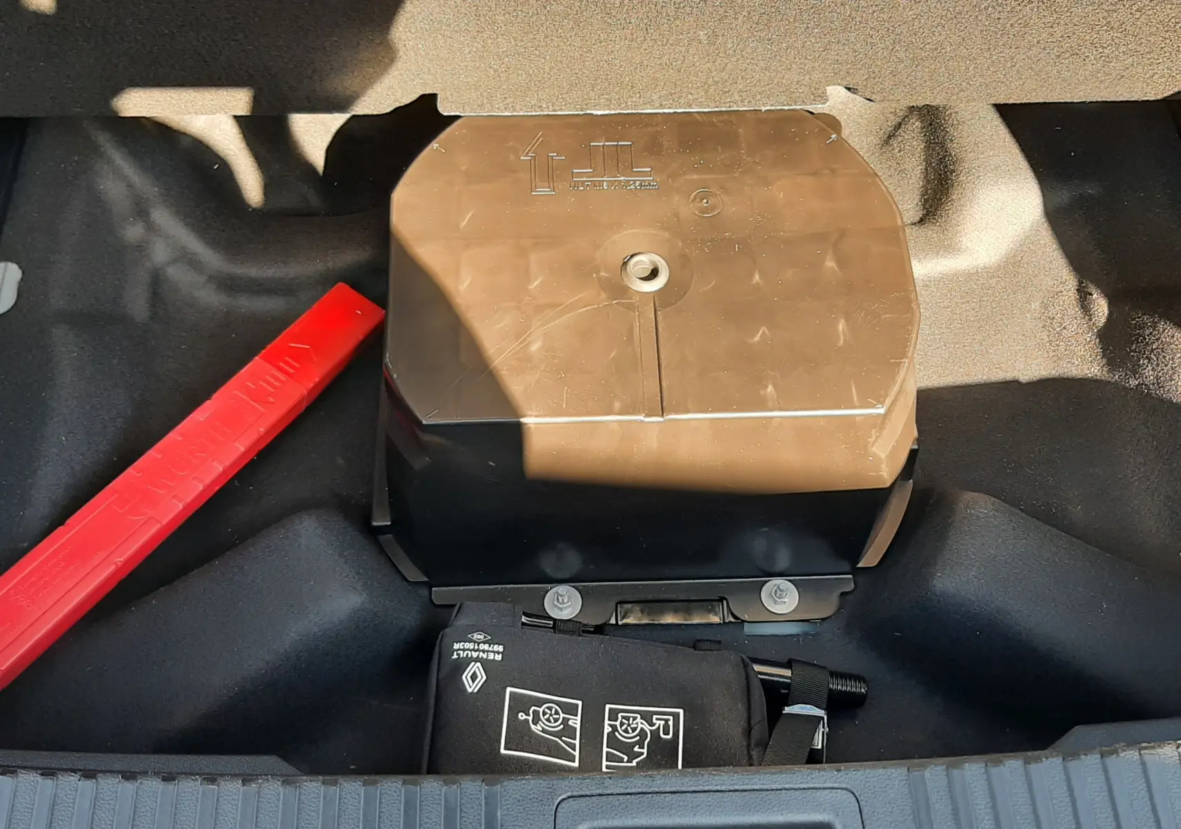 Vue rapprochée du compartiment de rangement sous le coffre du Renault Austral 2025, avec kit de sécurité et boîte noire.