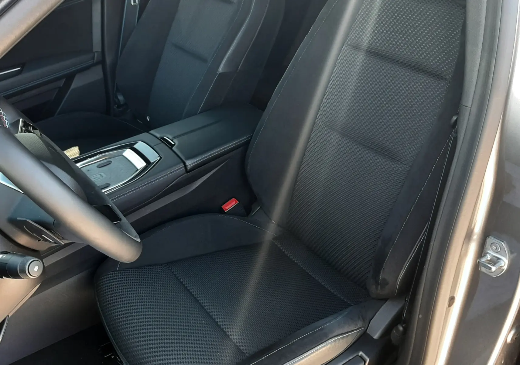 Vue intérieure côté conducteur du Renault Austral 2025, sièges noirs en tissu et cuir avec surpiqûres blanches.