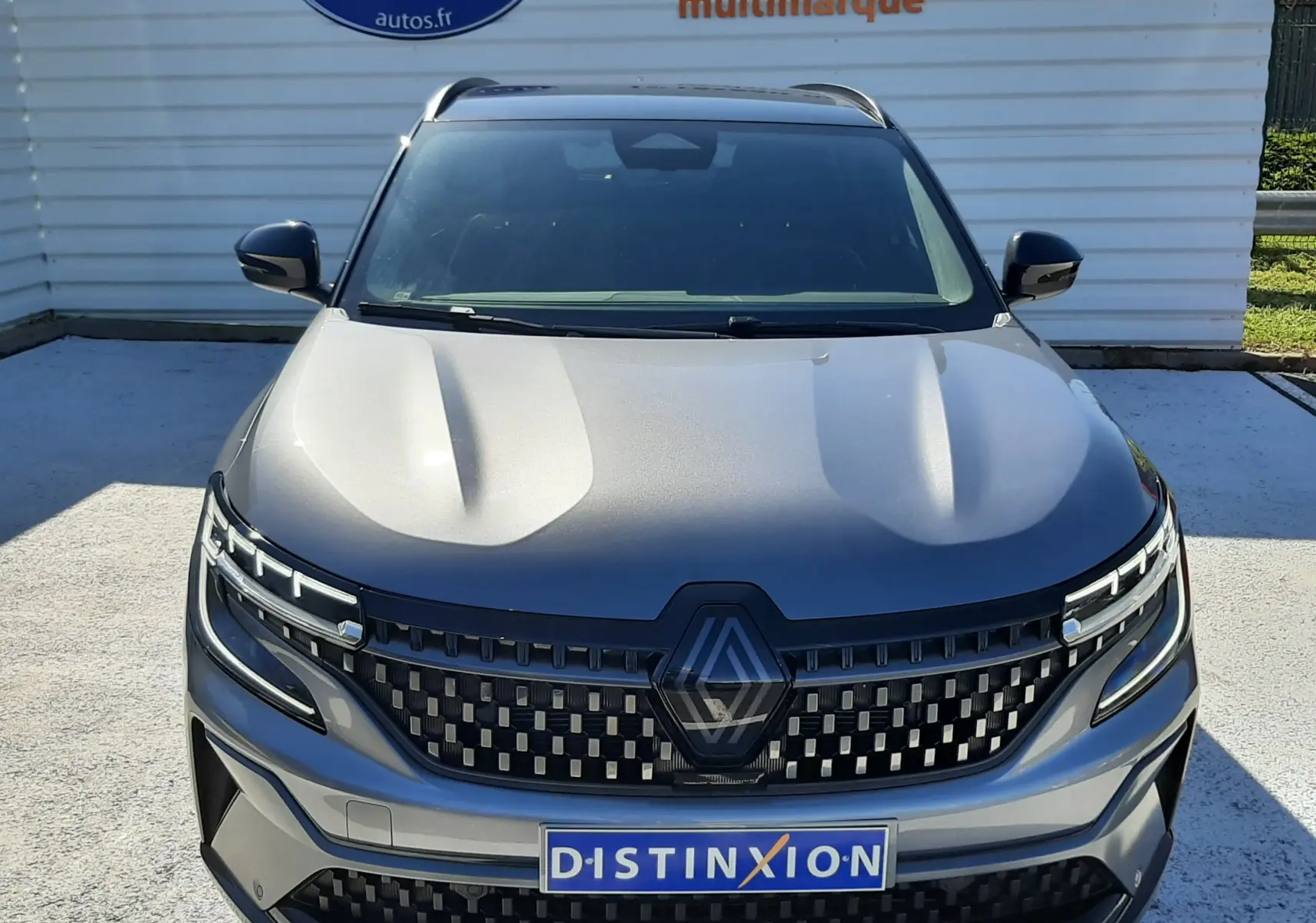 Vue de face du Renault Austral E-Tech Full Hybrid gris schiste avec toit noir, mettant en valeur sa calandre distinctive et ses phares LED.