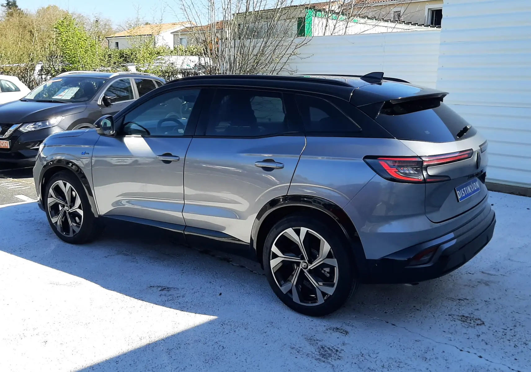 Vue 3/4 arrière droite d'un Renault Austral E-Tech gris schiste avec toit noir, jantes alliage et feux arrière LED distinctifs.