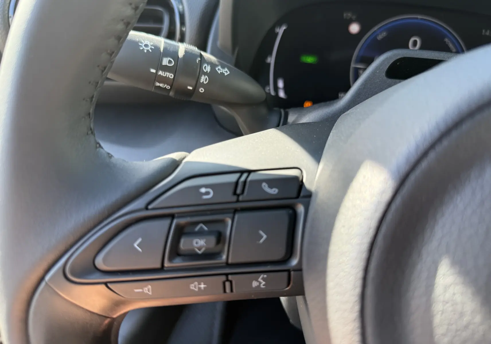 Gros plan sur les commandes au volant côté gauche de la Toyota Yaris Cross 2026 gris atlas, avec tableau de bord en arrière-plan.