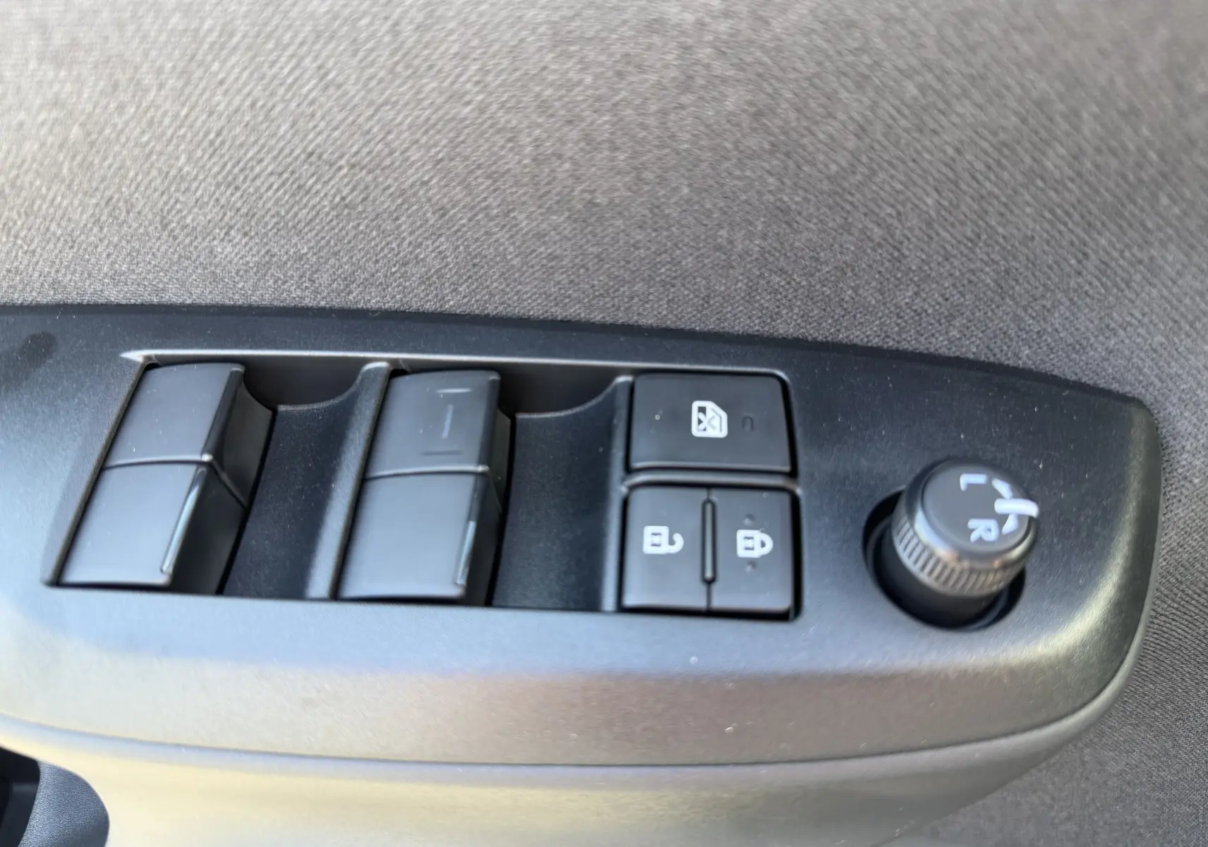 Vue rapprochée des commandes de lève-vitres et réglage des rétroviseurs sur la porte côté gauche d'une Toyota Yaris Cross gris atlas.