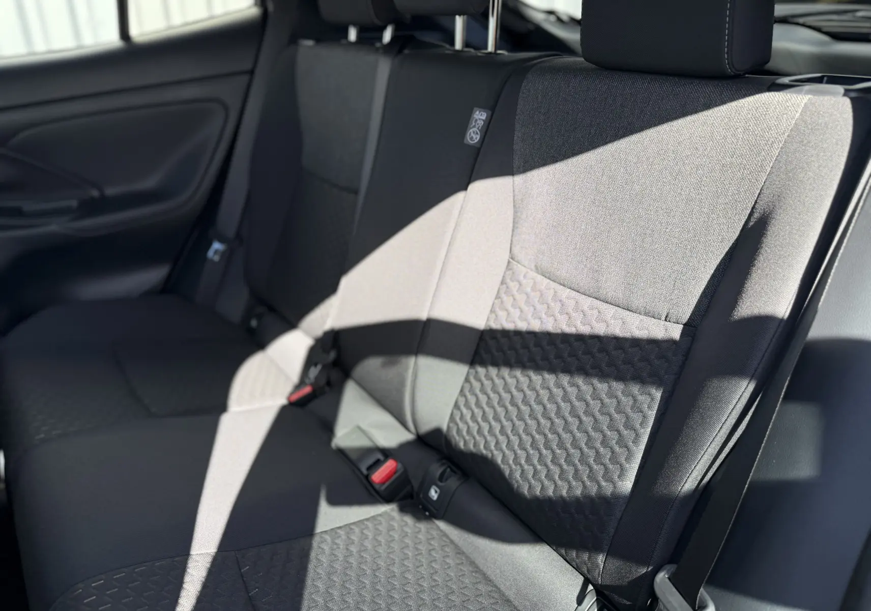 Vue rapprochée des sièges arrière en tissu gris foncé de la Toyota Yaris Cross 2026, avec ceinture de sécurité visible.