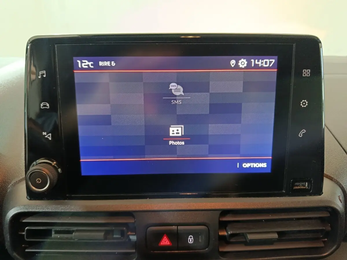 Écran tactile central du tableau de bord du Citroën Berlingo blanc, affichant menu SMS et photos.