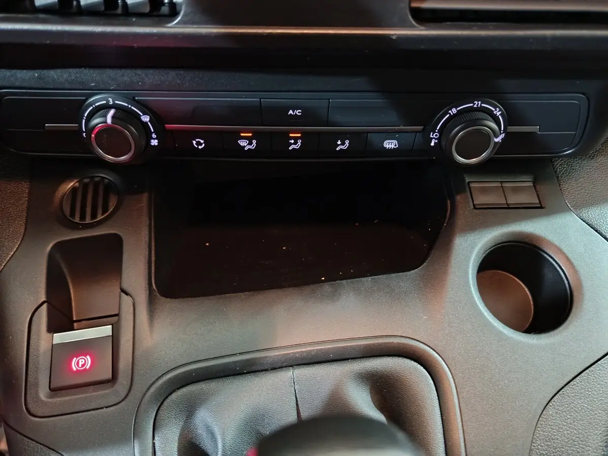 Vue rapprochée de la console centrale noire du Citroën Berlingo 2021, avec commandes climatisation et frein à main électrique allumé.