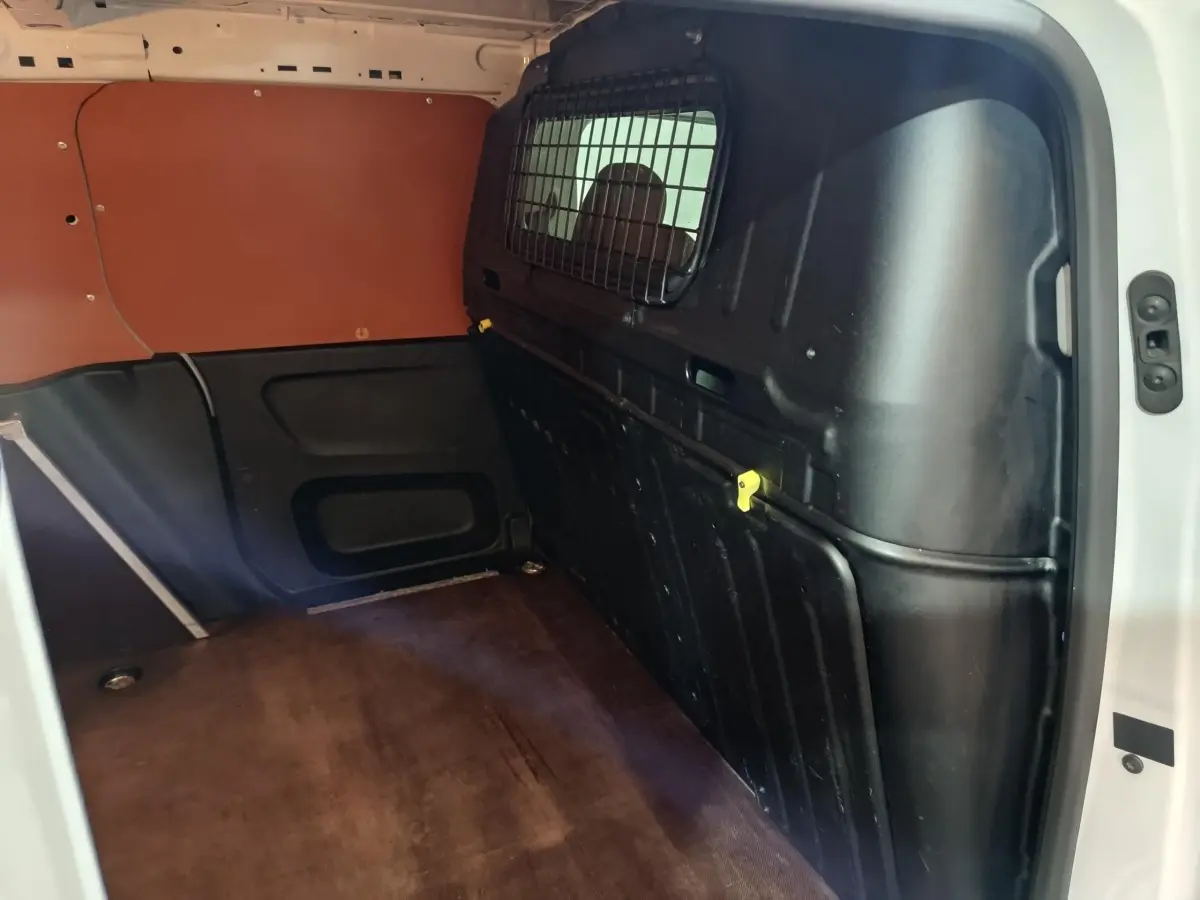 Vue intérieure côté droit du coffre blanc Citroën Berlingo 2021 avec cloison pleine noire et plancher marron.