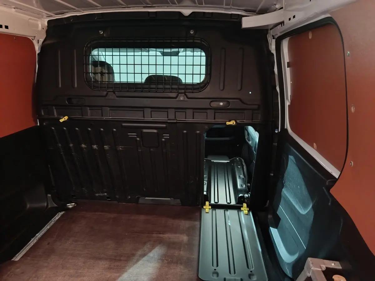 Vue intérieure du coffre du Citroën Berlingo blanc 2021, avec cloison pleine et plancher métallique visible.
