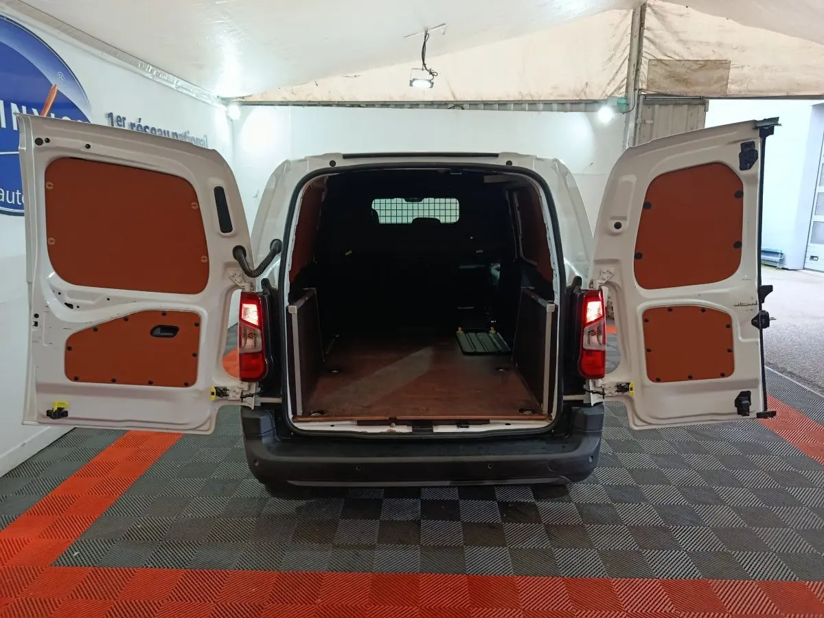 Vue arrière d’un Citroën Berlingo blanc 2021 avec portes ouvertes dévoilant l’espace de chargement vide et cloison pleine.