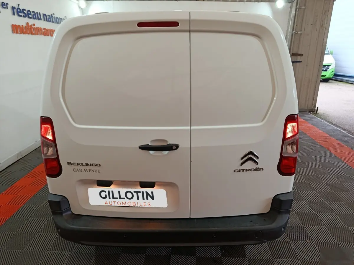 Vue arrière d’un utilitaire Citroën Berlingo blanc avec portes battantes et feux arrière allumés.