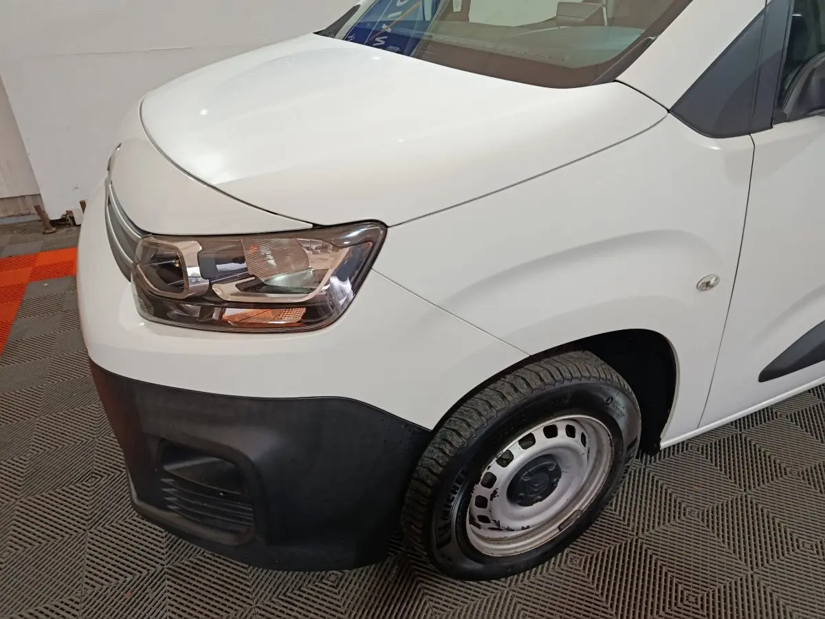 Vue 3/4 avant droit du Citroën Berlingo blanc avec pare-chocs noir et jante acier simple.