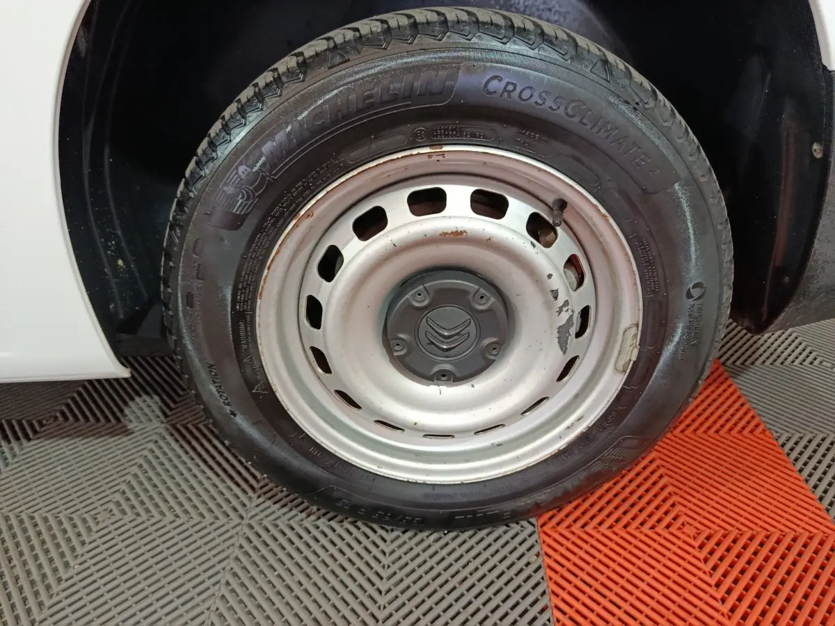 Gros plan sur la roue avant droite blanche d’un Citroën Berlingo 2021 avec jante acier et pneu Michelin CrossClimate.