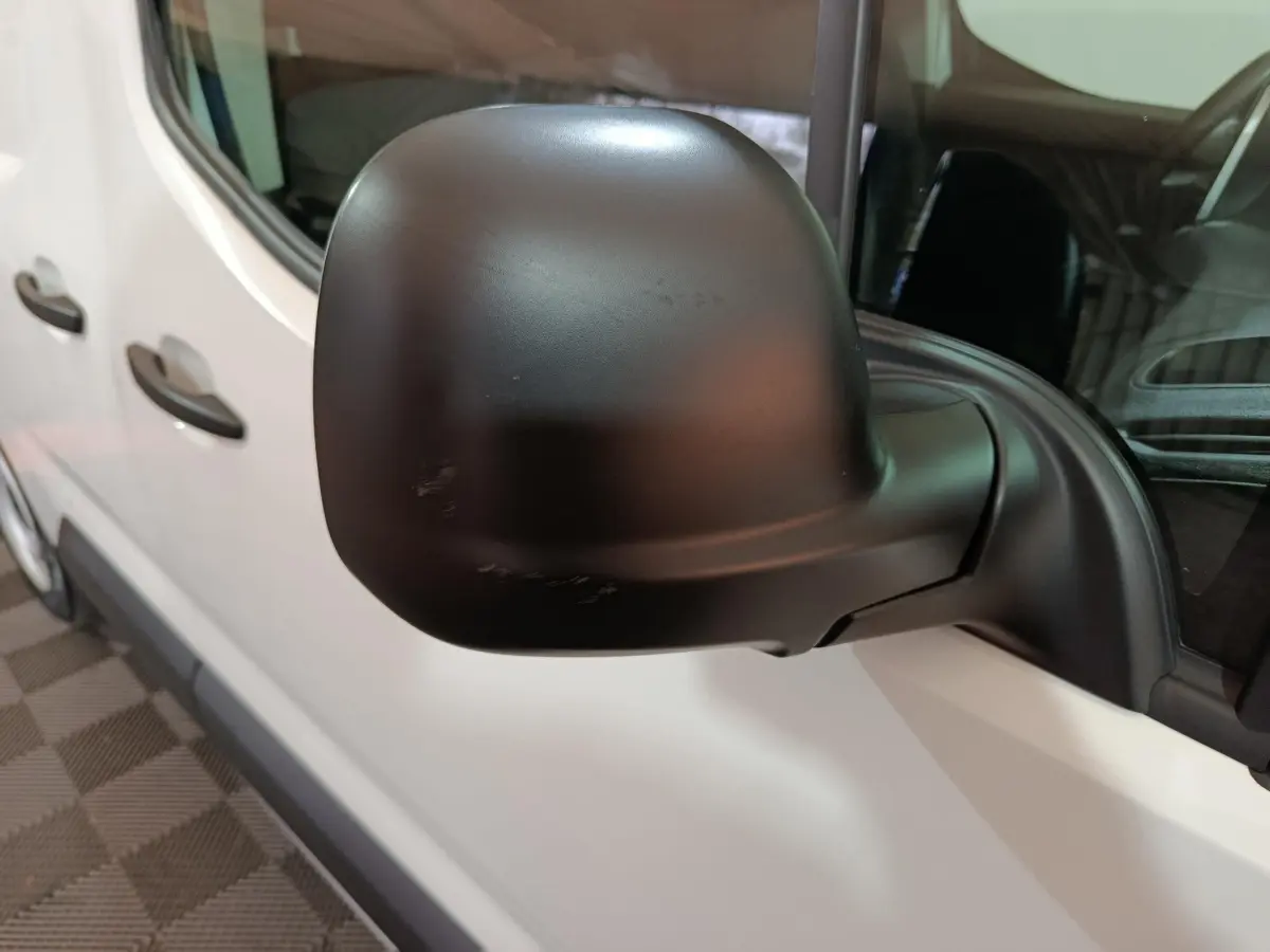 Gros plan sur le rétroviseur noir côté conducteur du Citroën Berlingo blanc, vue latérale gauche.