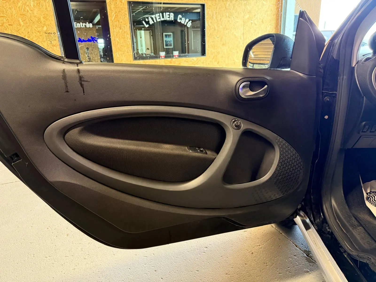 Vue intérieure de la porte avant gauche noire d'une Smart Fortwo Cabrio 2019 avec poignée et commande de vitre électrique.
