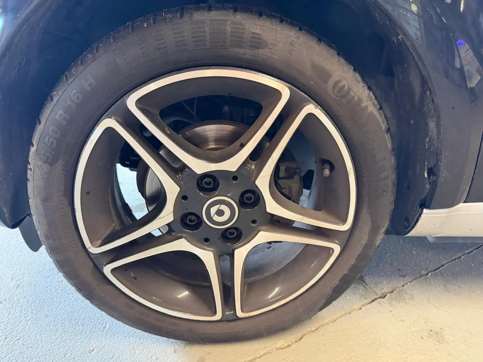 Gros plan sur la jante alu 16 pouces noire et argentée d'une Smart Fortwo Cabrio noire, vue côté roue arrière.