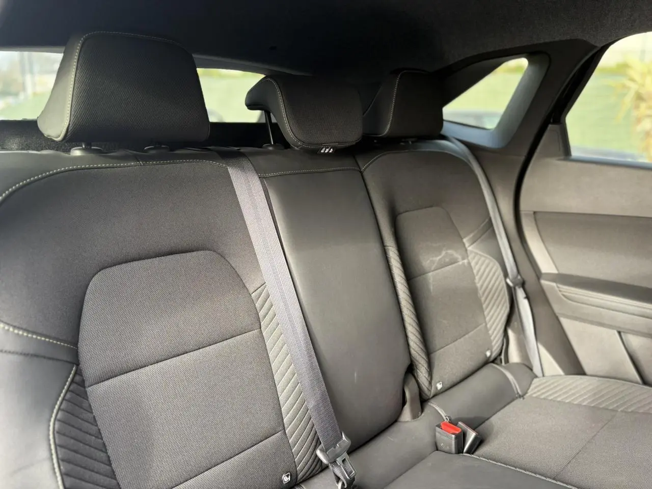 Vue intérieure de la banquette arrière noire du Renault SYMBIOZ E-Tech avec appuie-têtes et ceintures visibles.