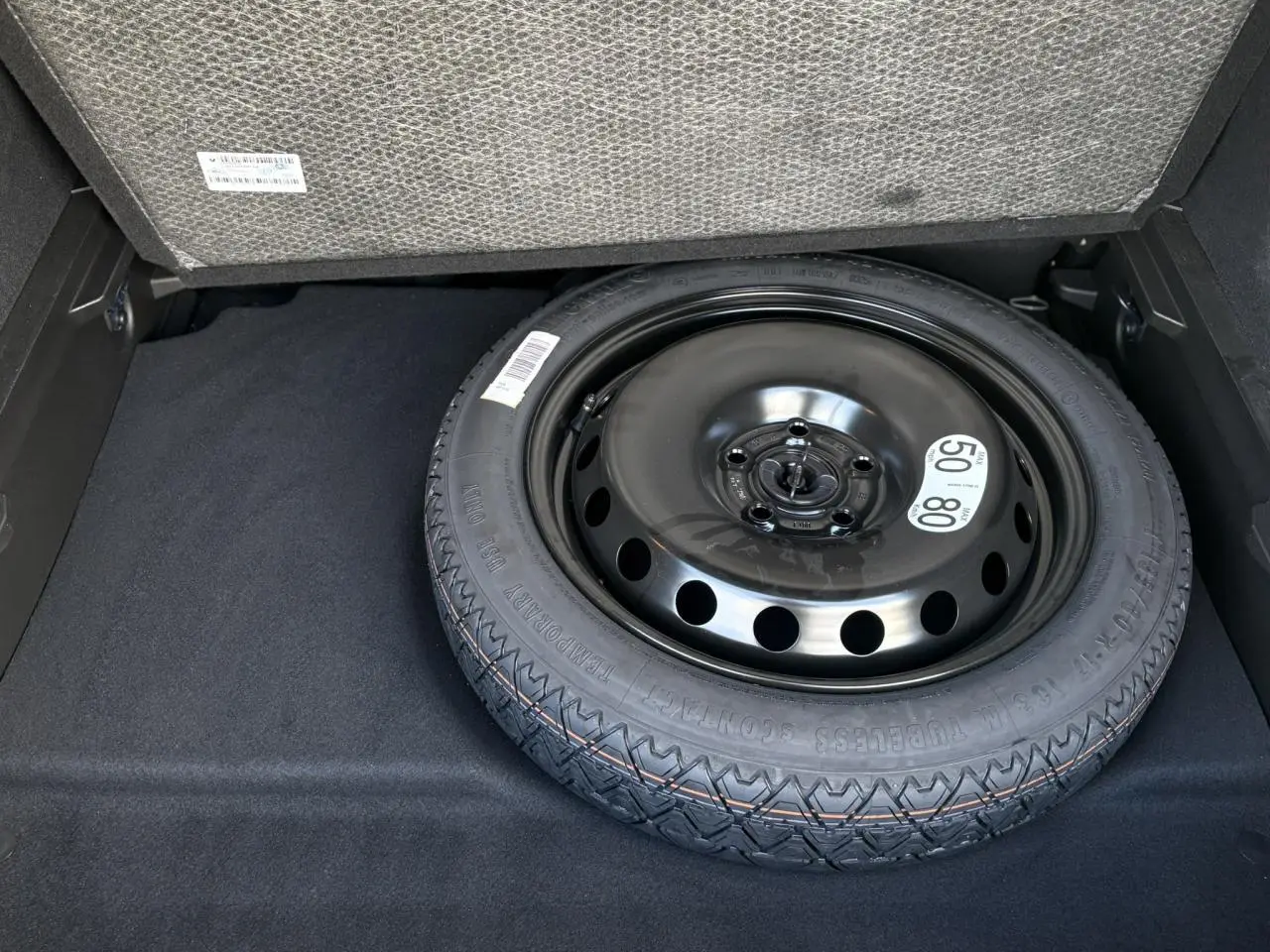 Gros plan sur la roue de secours temporaire noire dans le coffre du Renault SYMBIOZ E-Tech Full Hybrid 2025.