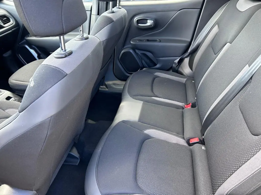 Vue intérieure côté droit des sièges arrière noirs du Jeep Renegade 2023, tissu avec ceintures de sécurité visibles.