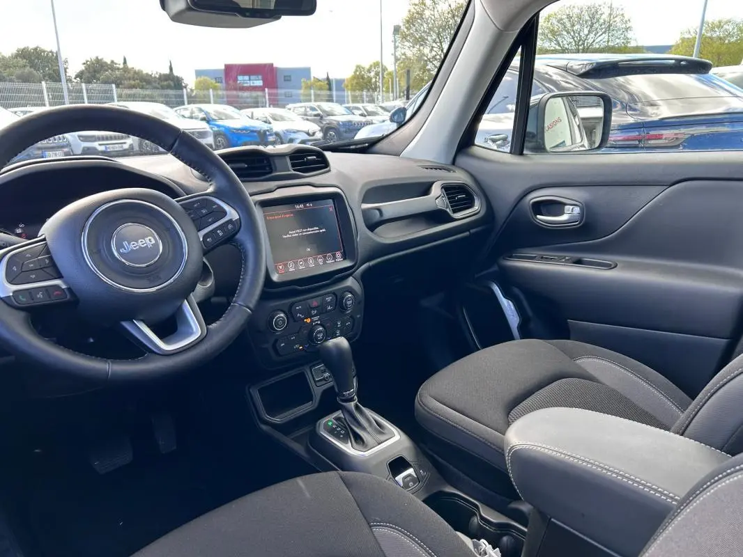 Vue intérieure côté conducteur du Jeep Renegade 2023, montrant le volant, écran tactile et accoudoir central noir.