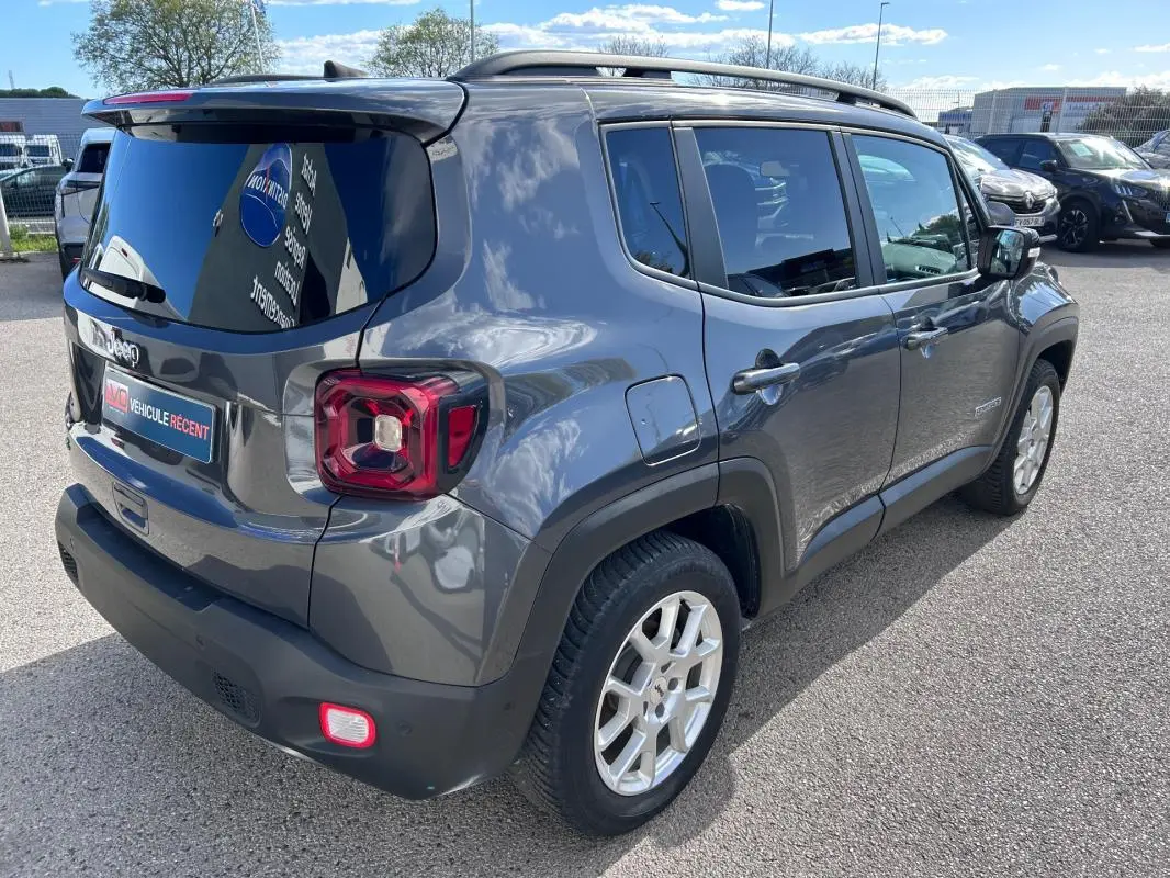 Vue 3/4 arrière droite d'un Jeep Renegade bleu foncé avec barres de toit et jantes alliage 17 pouces.