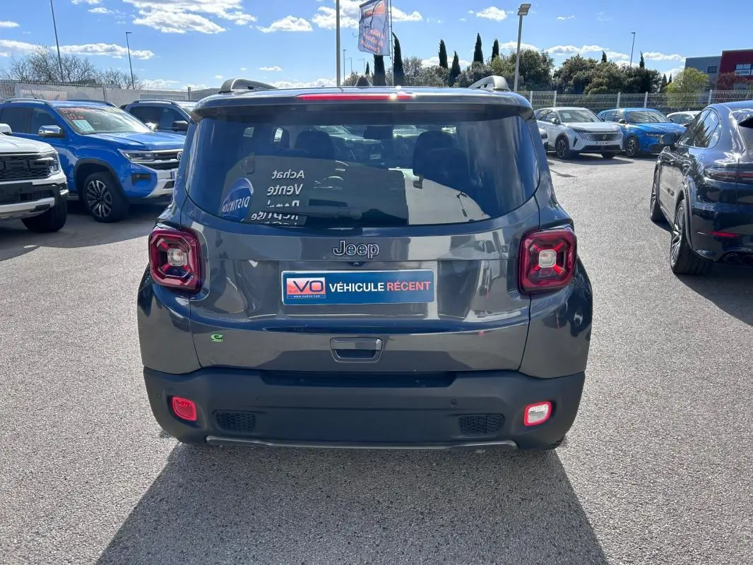 Vue arrière d’un Jeep Renegade bleu foncé 2023 avec feux carrés caractéristiques et barres de toit visibles.