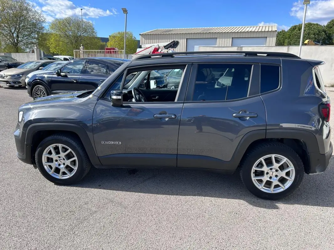 Vue de profil côté gauche d’un Jeep Renegade bleu foncé 2023 avec barres de toit et jantes alliage 17 pouces.