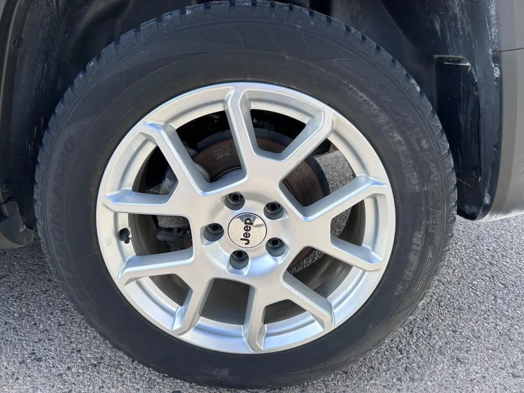 Gros plan sur la jante alliage 17 pouces argentée d’un Jeep Renegade bleu foncé, avec logo Jeep au centre.