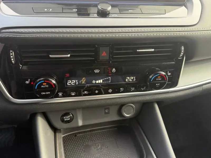 Vue rapprochée de la console centrale du Nissan Qashqai Hybrid e-POWER 2025, avec commandes climatisation et bouton start/stop.
