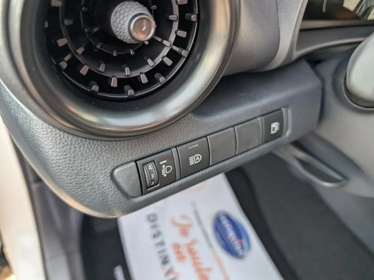 Détail des commandes côté gauche du tableau de bord du Toyota C-HR blanc 2024, avec aérateur rond et réglages lumineux.