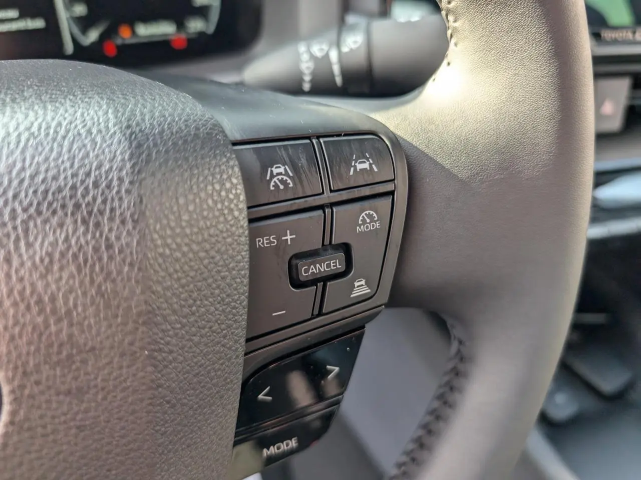 Gros plan sur les commandes de régulateur de vitesse au volant du Toyota C-HR blanc 2024, version hybride.