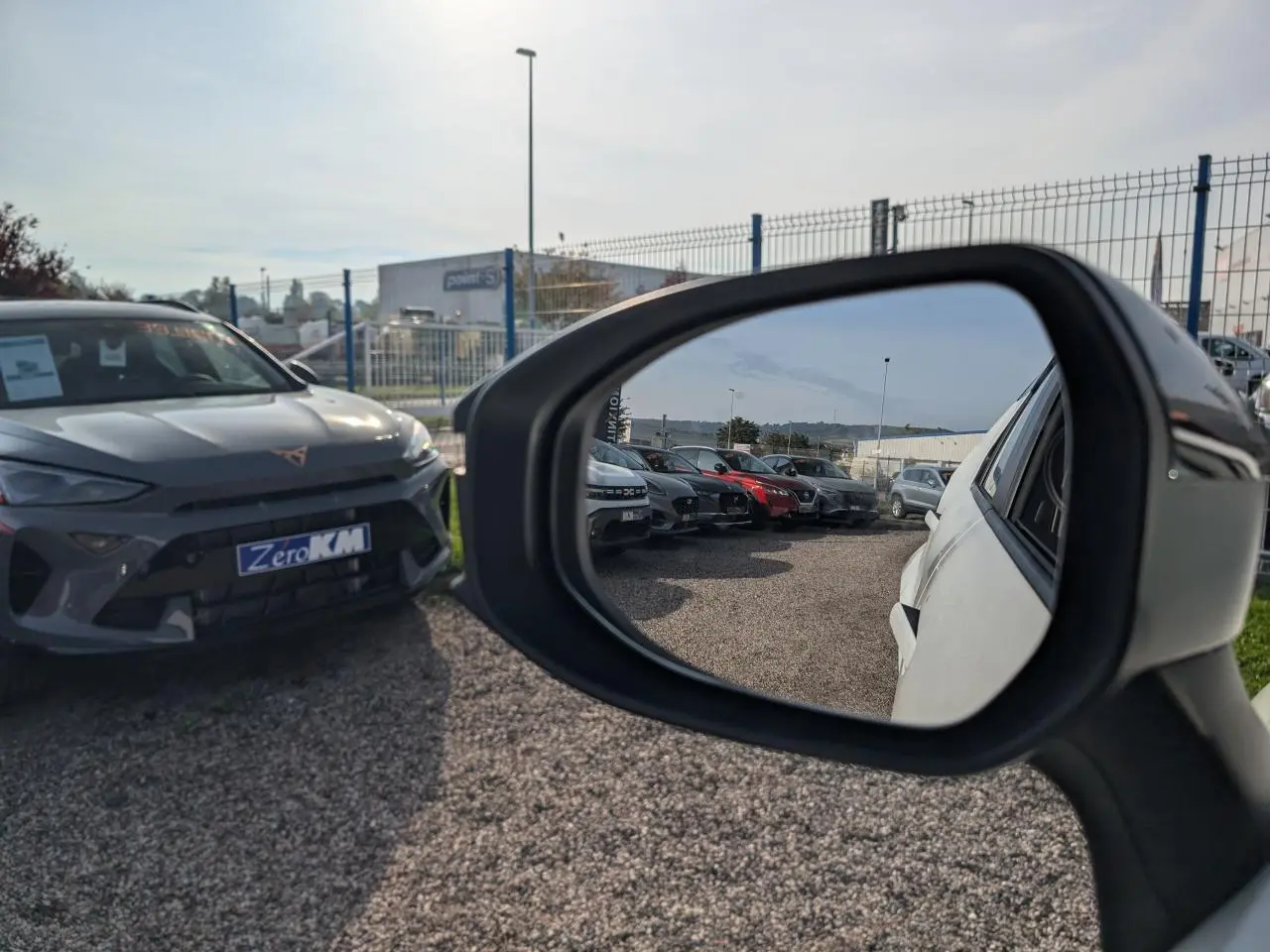 Rétroviseur côté droit montrant la carrosserie blanche d’un Toyota C-HR 1.8 Hybrid 2024 en extérieur.