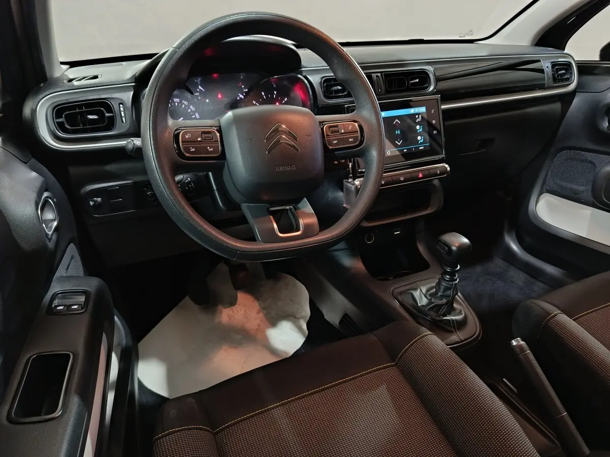 Vue intérieure avant de la Citroën C3 2024 gris foncé, volant multifonctions, écran tactile central et boîte manuelle.