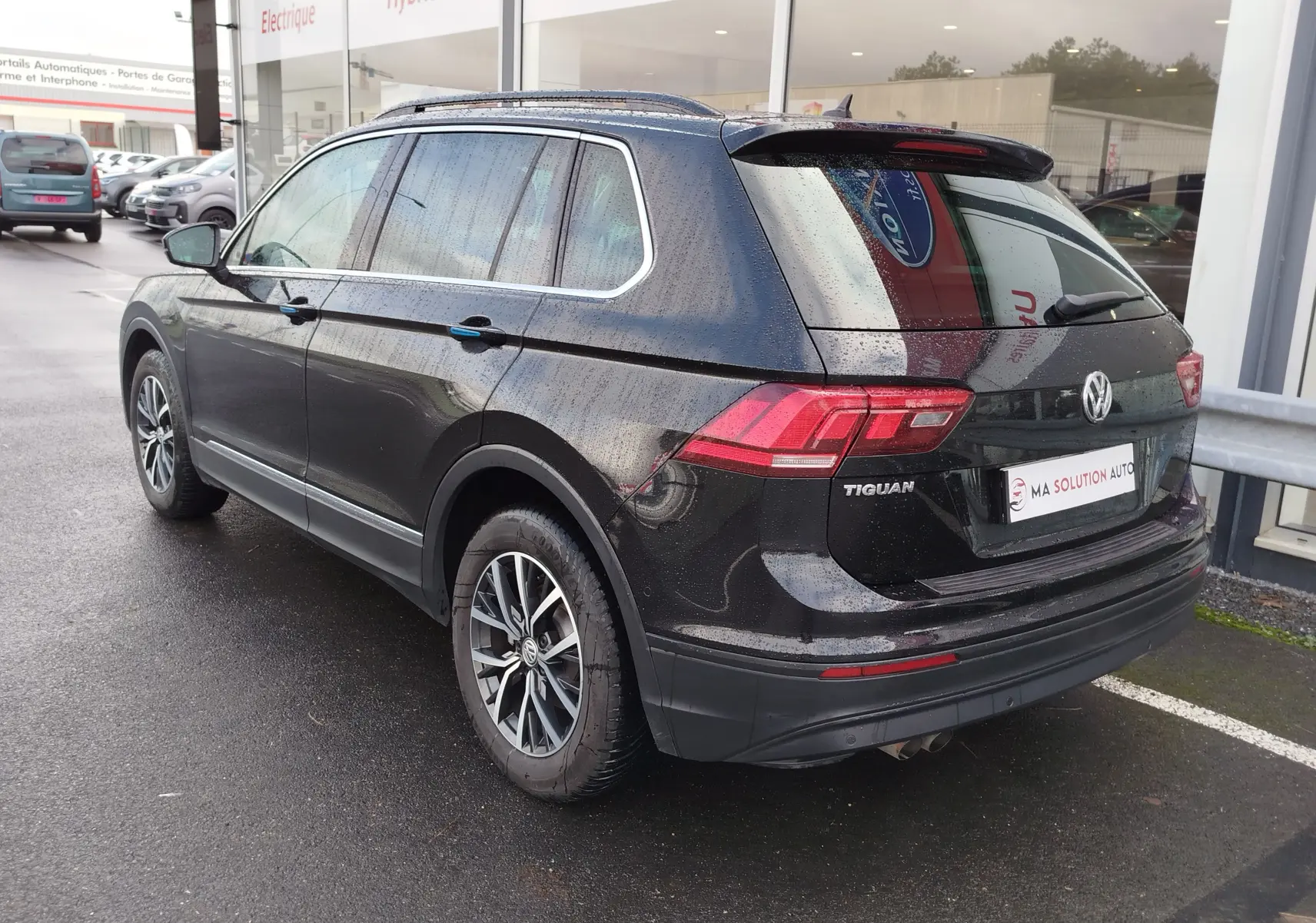 Volkswagen Tiguan 2.0 TDI noir nacré vu en 3/4 arrière droit, avec jantes alliage et feux arrière LED visibles.