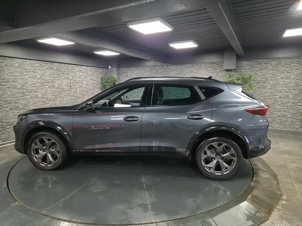 Vue de profil côté gauche d’un CUPRA Formentor gris métallisé avec jantes alliage 18'' et bas de caisse noir contrastant.