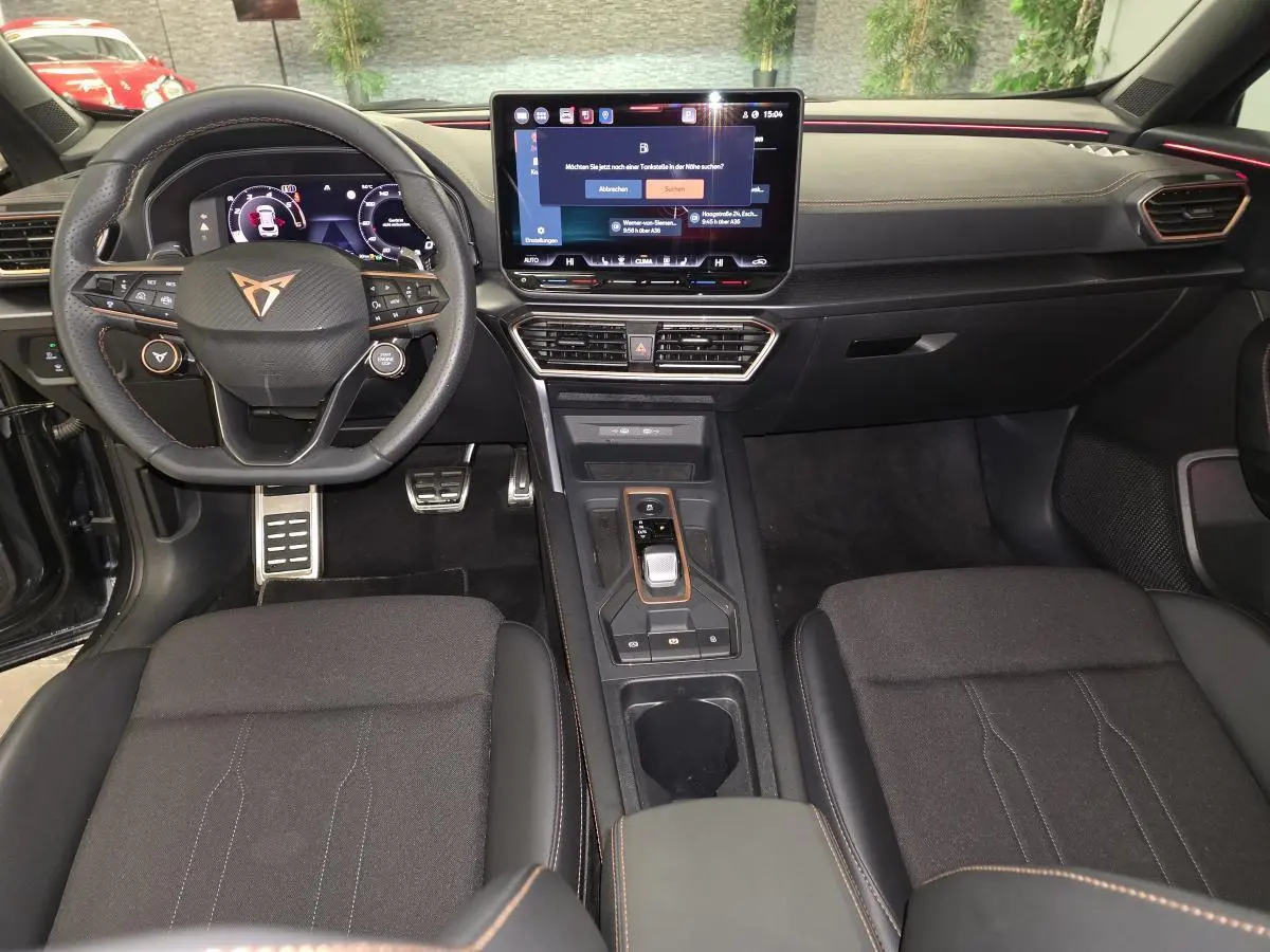 Vue intérieure avant du Cupra Formentor 2025 avec tableau de bord noir, écran tactile central et volant sport à logo cuivre.