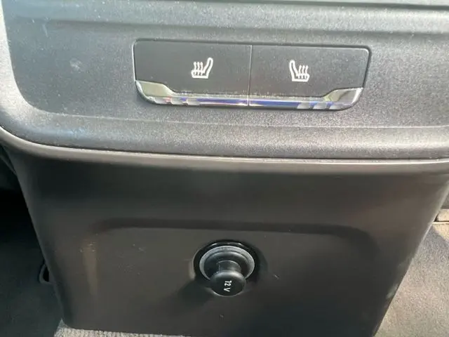 Gros plan sur les commandes des sièges chauffants et prise 12V à l'arrière du Porsche Macan gris diesel 2015.