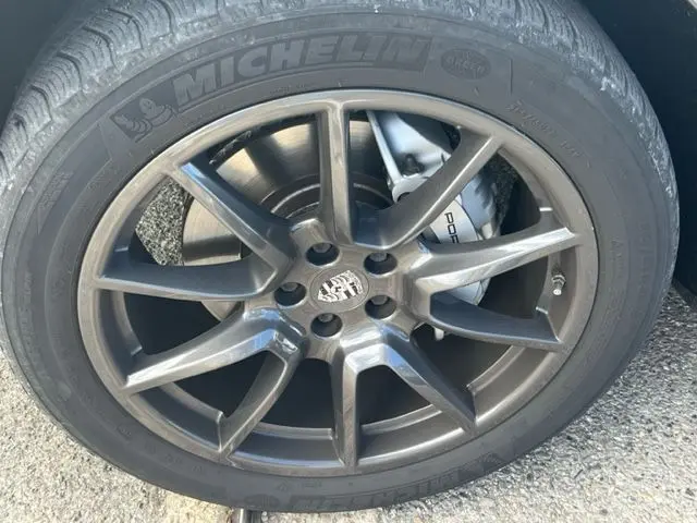 Gros plan sur la jante gris foncé d'une Porsche Macan 2015, avec étrier de frein Porsche et pneu Michelin visible.