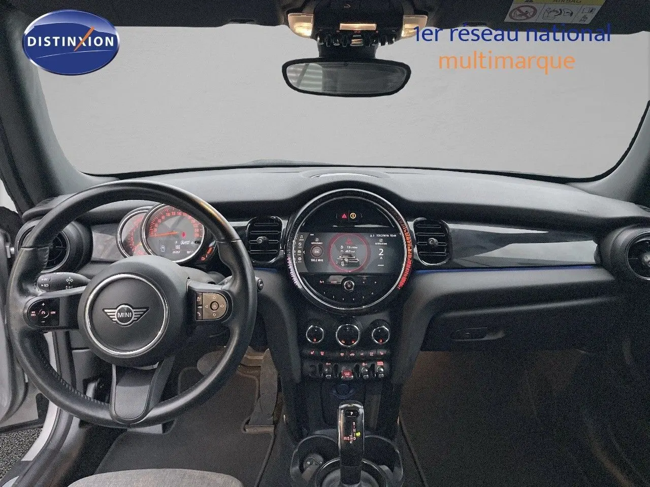 Intérieur noir du MINI Cabriolet F57 2023, vue frontale sur le tableau de bord et volant avec écran central rond.