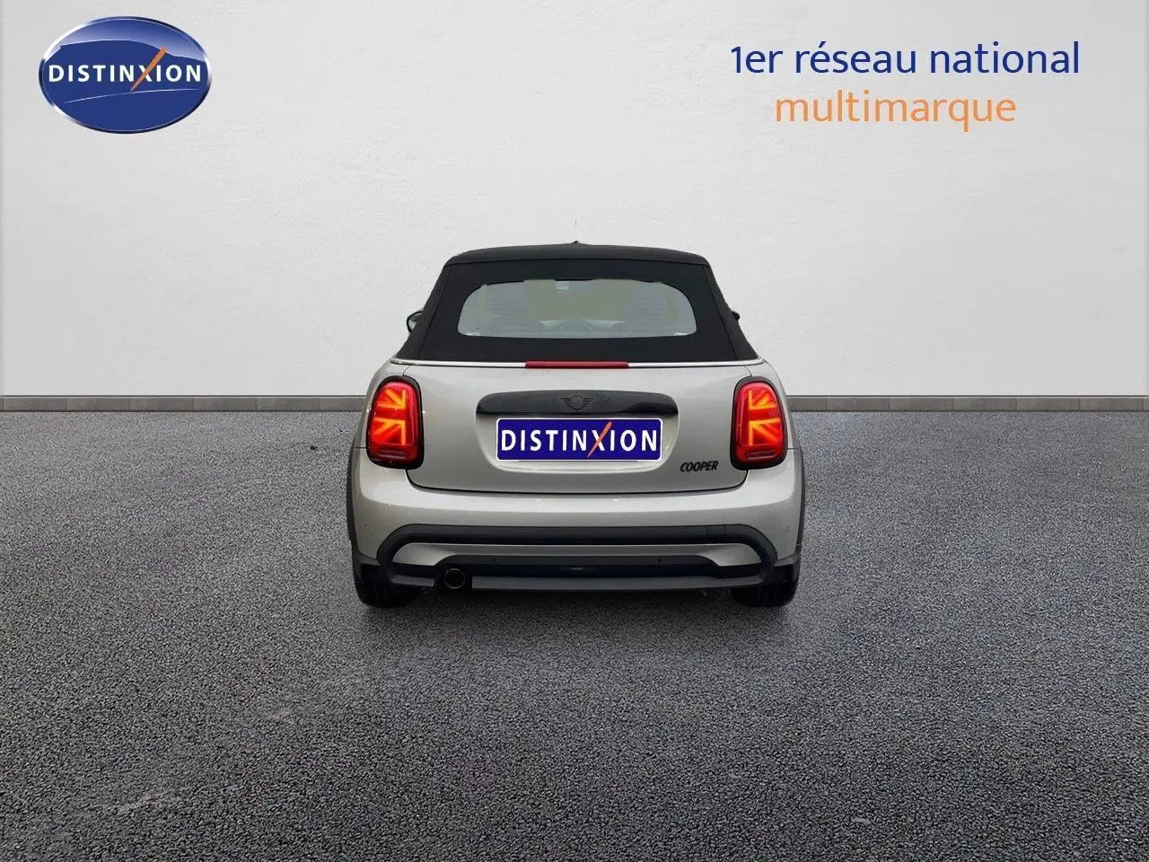 Vue arrière d'une MINI Cabriolet F57 Melting Silver avec toit noir relevé et feux arrière allumés.
