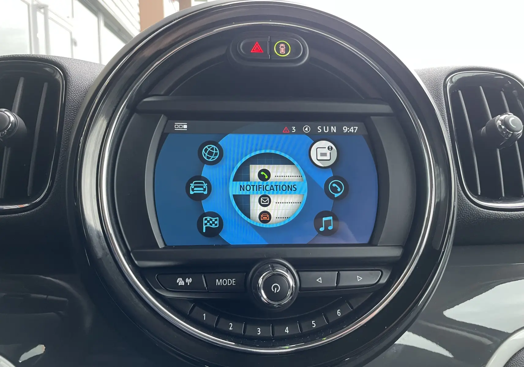 Écran central tactile rond affichant le menu notifications dans l'habitacle gris-noir du MINI Countryman hybride rechargeable.