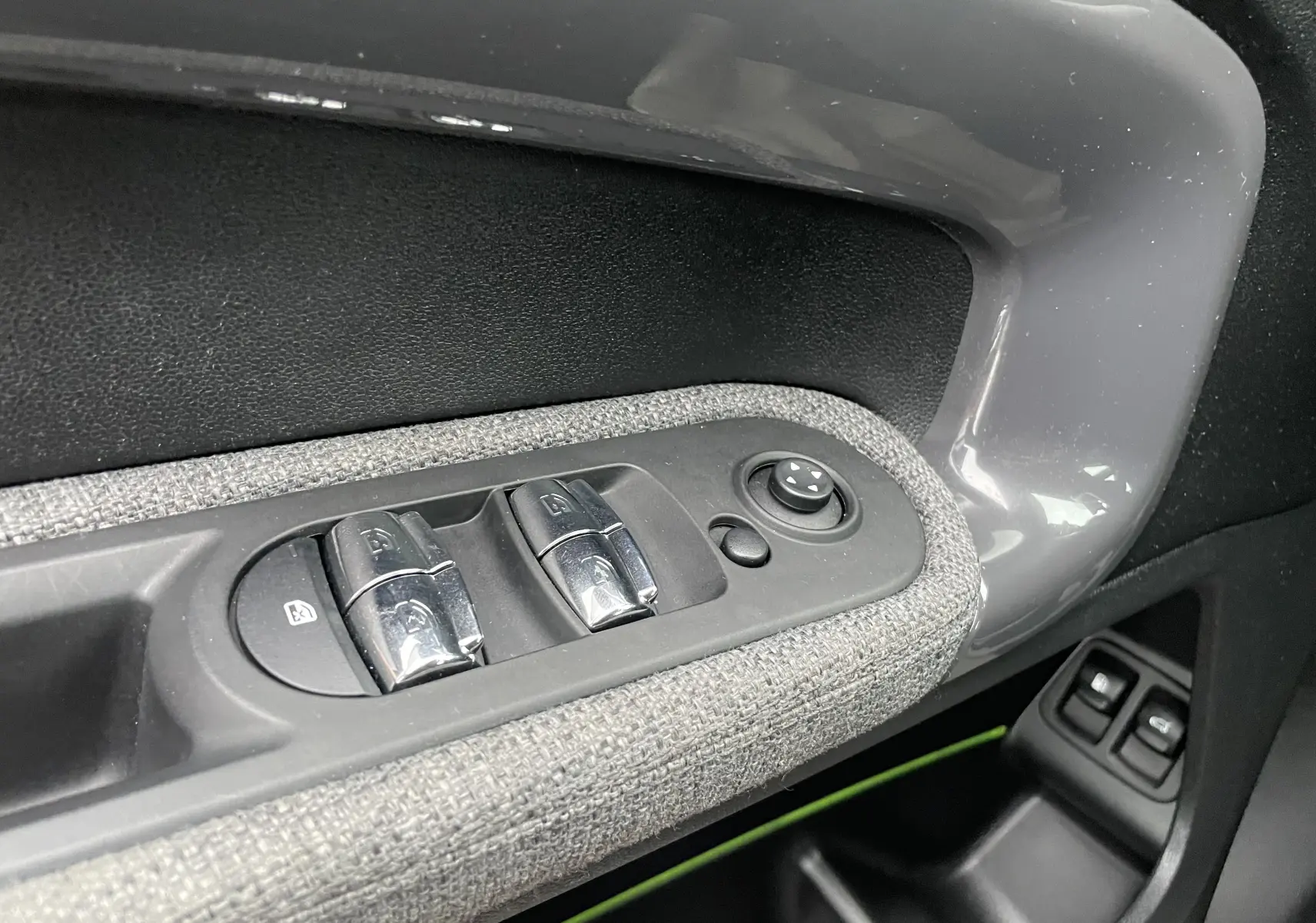 Gros plan sur les commandes de lève-vitres côté gauche d'une MINI Countryman bleu Island Metal avec habillage tissu gris.