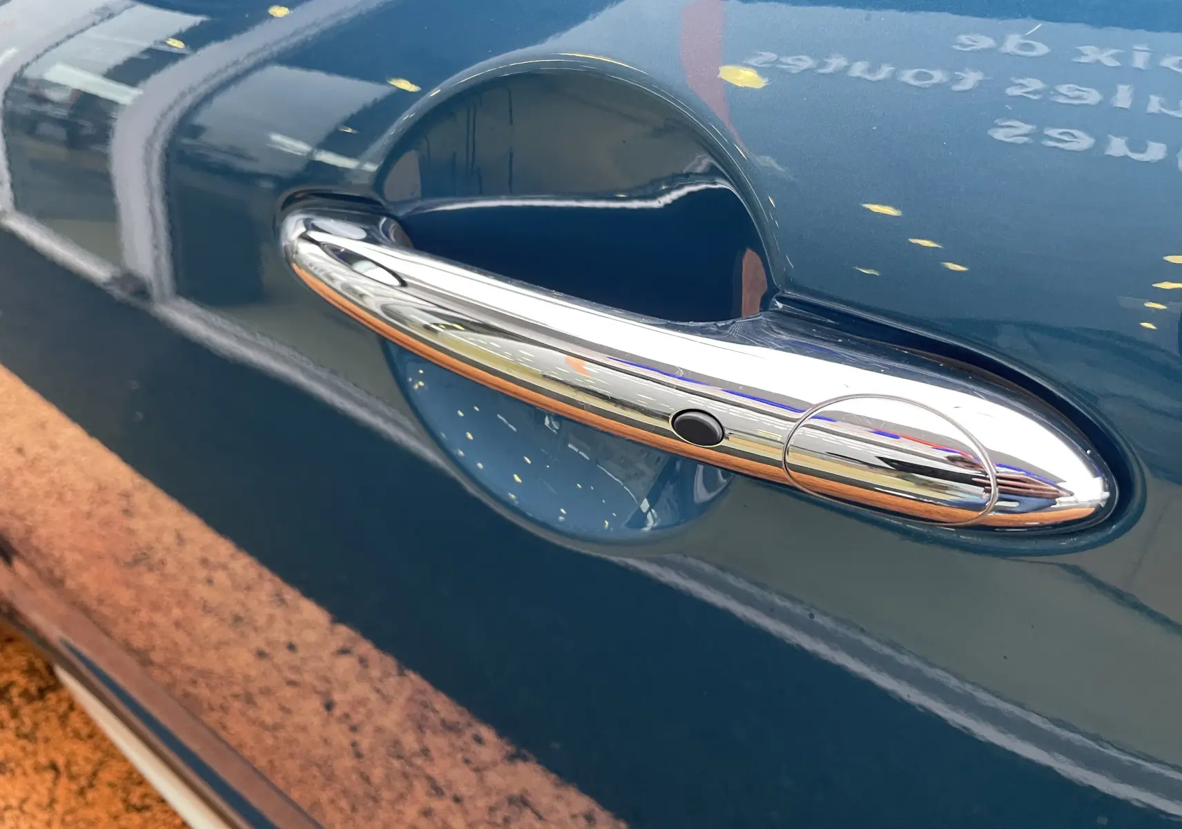 Poignée de porte chromée en gros plan sur la portière côté gauche d'une MINI Countryman bleu Island Metal hybride rechargeable.