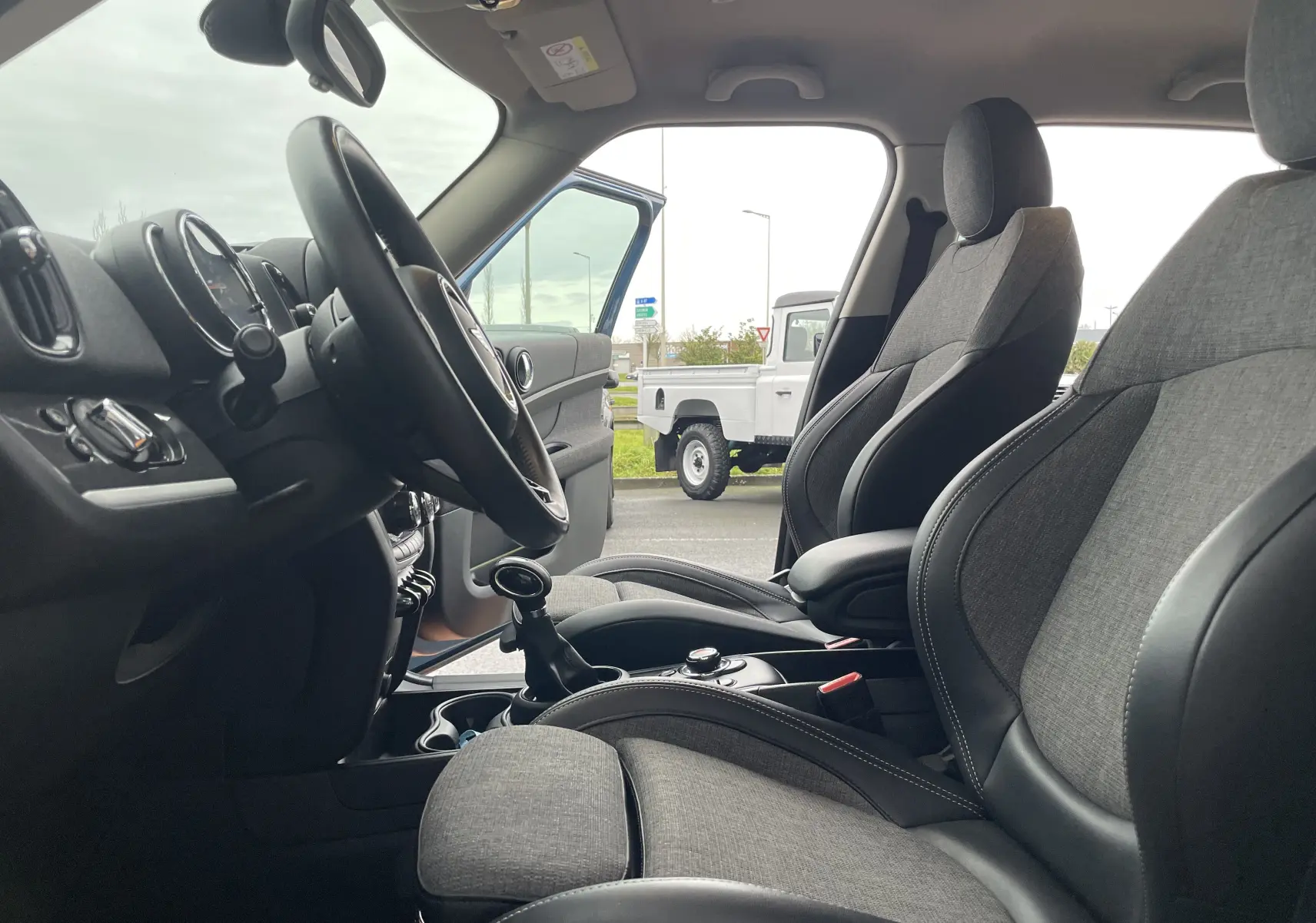Vue intérieure côté conducteur du MINI Countryman Cooper S hybride, sièges tissu gris foncé et volant noir visible.