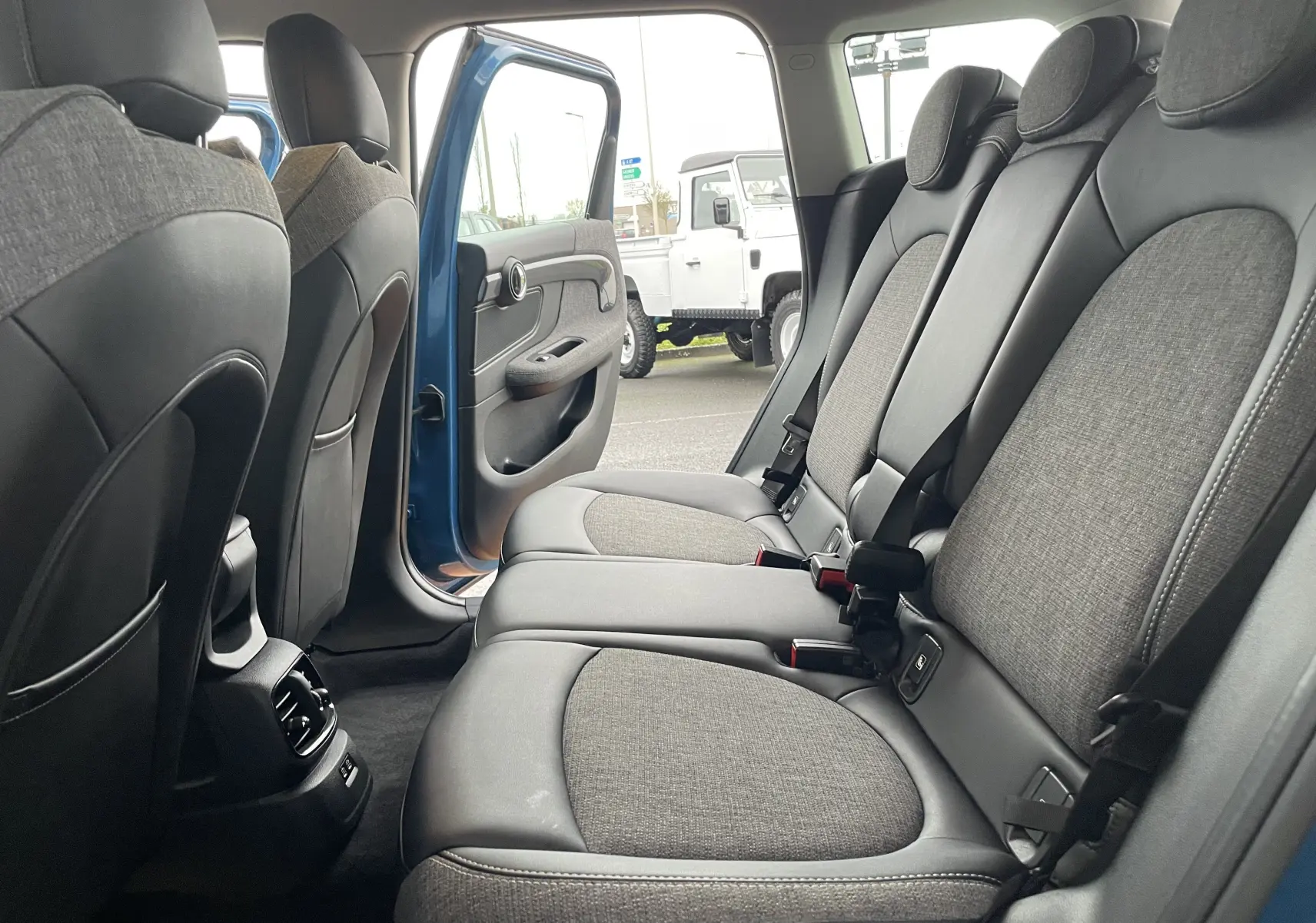 Vue intérieure côté droit des sièges arrière gris tissu et cuir d'un MINI Countryman bleu Island Metal avec porte ouverte.
