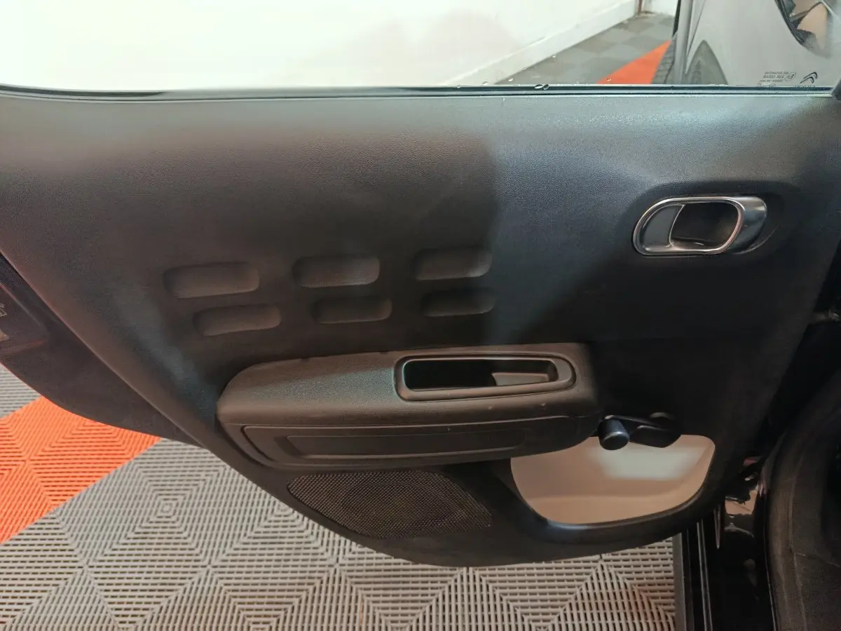 Vue intérieure de la porte arrière gauche noire de la Citroën C3 2024 avec poignée intégrée et manivelle de vitre.