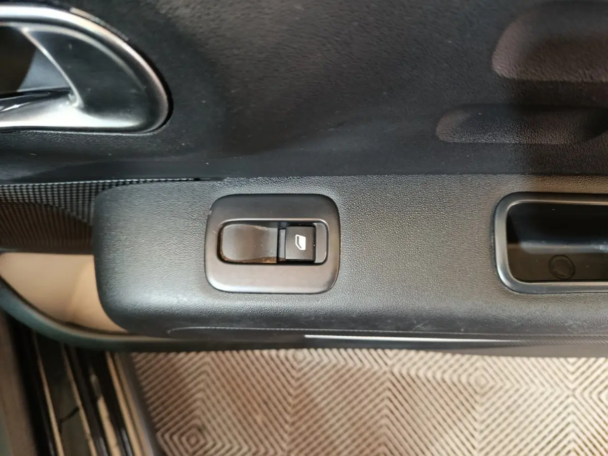 Gros plan sur le bouton de commande de la vitre électrique côté conducteur de la Citroën C3 noire 2024.