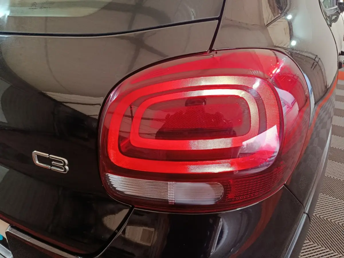 Gros plan sur le feu arrière droit rouge et blanc d’une Citroën C3 noire, avec logo C3 visible sur la carrosserie.